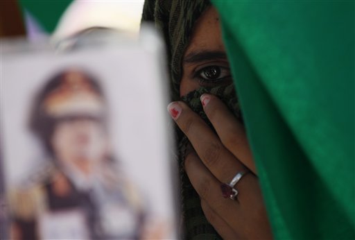 In this photo taken on a government-organized tourm a Libyan student holds a portrait of Libyan leader Moammar Gadhafi, outside the damaged university building in Tripoli, Libya, on Saturday, June 18, 2011. Libyan officials claim that one of the buildings at the university complex was recently hit by a NATO airstrike. (AP Photo/Ivan Sekretarev) (AP)