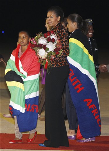 First lady Michelle Obama holds a bouquet of flowers, and daughters Malia, right, and Sasha, are draped in blankets given to them upon landing in Pretoria, en route to Johannesburg, South Africa, Monday, June 20, 2011, as they begin their week long trip to Africa. (AP Photo/Charles Dharapak, Pool) (AP)