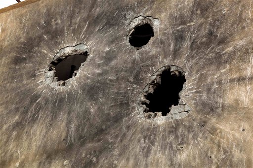 In this photo taken Sunday, May 22, 2011, holes caused by heavy ammunition are seen on the side wall of a building in Tripoli Street, the center of the fighting between forces loyal to Libyan-leader Moammar Gadhafi and rebels in downtown Misrata, Libya. Since the weeks-long siege of the city ended in mid-May, Misrata residents make pilgrimages to Tripoli Street, site of the fiercest fighting in the battle for Libya between the rebels and Moammar Gadhafi's forces. People gawk at the wreckage of bombed-out buildings with gaping holes and walls pocked by bullets, and shoot photos of charred hulks of tanks, rubble-strewn streets and a side walk museum featuring drumloads of bullet casings, uniforms of dead enemies, and unexploded munitions. (AP Photo/Rodrigo Abd) (AP)