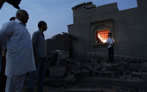 In this photo taken on a government organized tour, local residents stand next to a damaged house in Tripoli, Libya, on Sunday, June 5, 2011. Libyan officials claim that during a NATO airstrike, a rocket targeted a nearby military site hit a residential area and damaged several houses. (AP Photo/Ivan Sekretarev) (AP)