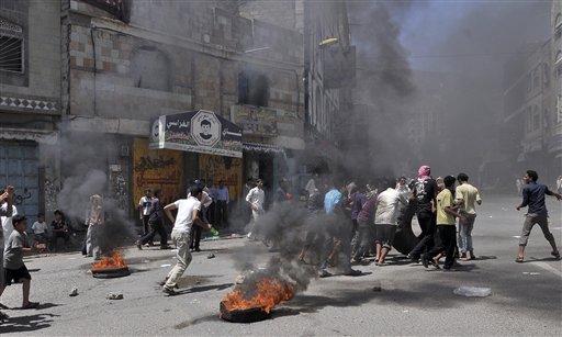 Anti-government protestors prepare to burn a tyre as they block the road during  clashes with Yemeni security forces in Taiz, Yemen, Tuesday, May 31, 2011. Heavy fighting resumed Tuesday in Yemen's capital between government troops and followers of the country's most powerful tribal leader, ending a brief cease-fire and again raising the prospect that Yemen's political crisis could veer into civil war.(AP Photo/Yemen Lens) (AP)