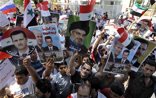Protesters shout slogans as they carry pictures of Syrian President Bashar Assad, left, his father Hafez Assad, second from left, Hezbollah leader Sheik Hassan Nasrallah, center, and Syrian flags, during a demonstration to show their support for the Syrian President in front of the Russian Embassy, in Beirut, Lebanon, Sunday, June 19, 2011. (AP Photo/Bilal Hussein) (AP)