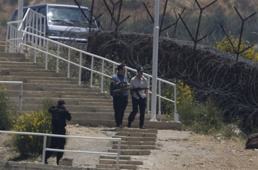 Seen from Majdal Shams, an  armed Syrian security officer on a hill over looking Majdal Shams near  the border between Syria and Israel in the Golan Heights early Monday, June 6, 2011.  Syrian police blocked dozens of pro-Palestinian protesters from approaching the Israeli frontier on Monday. The toll of demonstrators killed trying to break through into the Israeli-controlled Golan Heights rose to 23. Syrian police set up a pair of checkpoints, including one a half-mile (kilometer) from the border. Nearly 20 protesters, some waving Syrian flags, began walking down a hill leading to the border when two police officers blocked their advance by extending their arms. (AP Photo/Ariel Schalit) (AP)