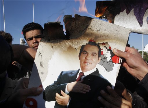 FILE - In this Monday, Jan. 24, 2011 picture, protestors burn a photo of former Tunisian President Zine El Abidine Ben Ali during a demonstration against holdovers from Ben Ali's regime in the interim government in Tunis, Tunisia. Tunisia's former autocratic leader whose downfall triggered uprisings in the Arab world has condemned his upcoming trial in absentia in Tunis as a "shameful masquerade." Ben Ali - in exile in Saudi Arabia - also said Sunday, June 19, 2011 in a statement from his French lawyer that he didn't flBeee Tunisia but left to avoid "fratricidal and deadly confrontations." (AP Photo/Christophe Ena, File) (AP)