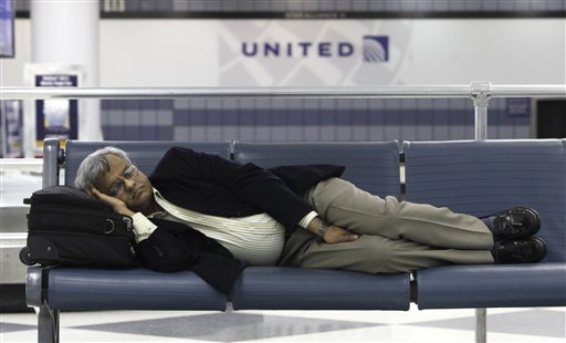 A stranded United Airlines passenger sleeps in Terminal 1 at O'Hare International Airport Saturday, June 18, 2011 in Chicago. Thousands of flyers were stranded Friday night in airports across the country when United Airlines computers crashed, interrupting departures and reservations and disrupting the airline's websites.  (AP Photo/Charles Rex Arbogast) (AP)