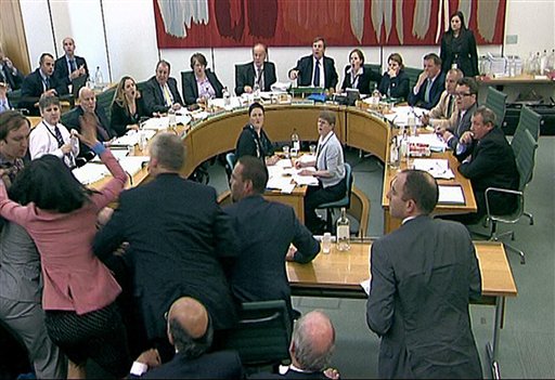 Committee members react after a protestor, left checked shirt , named on Twitter as Jonnie Marbles, tries to throw  a paper plate covered in shaving foam over Rupert Murdoch as he gave evidence to a House of Commons Committee in London, Tuesday July 19, 2011, on the News of the World phone hacking scandal.(AP Photo/pa)  UNITED KINGDOM OUT: NO SALES: NO ARCHIVE: (AP)