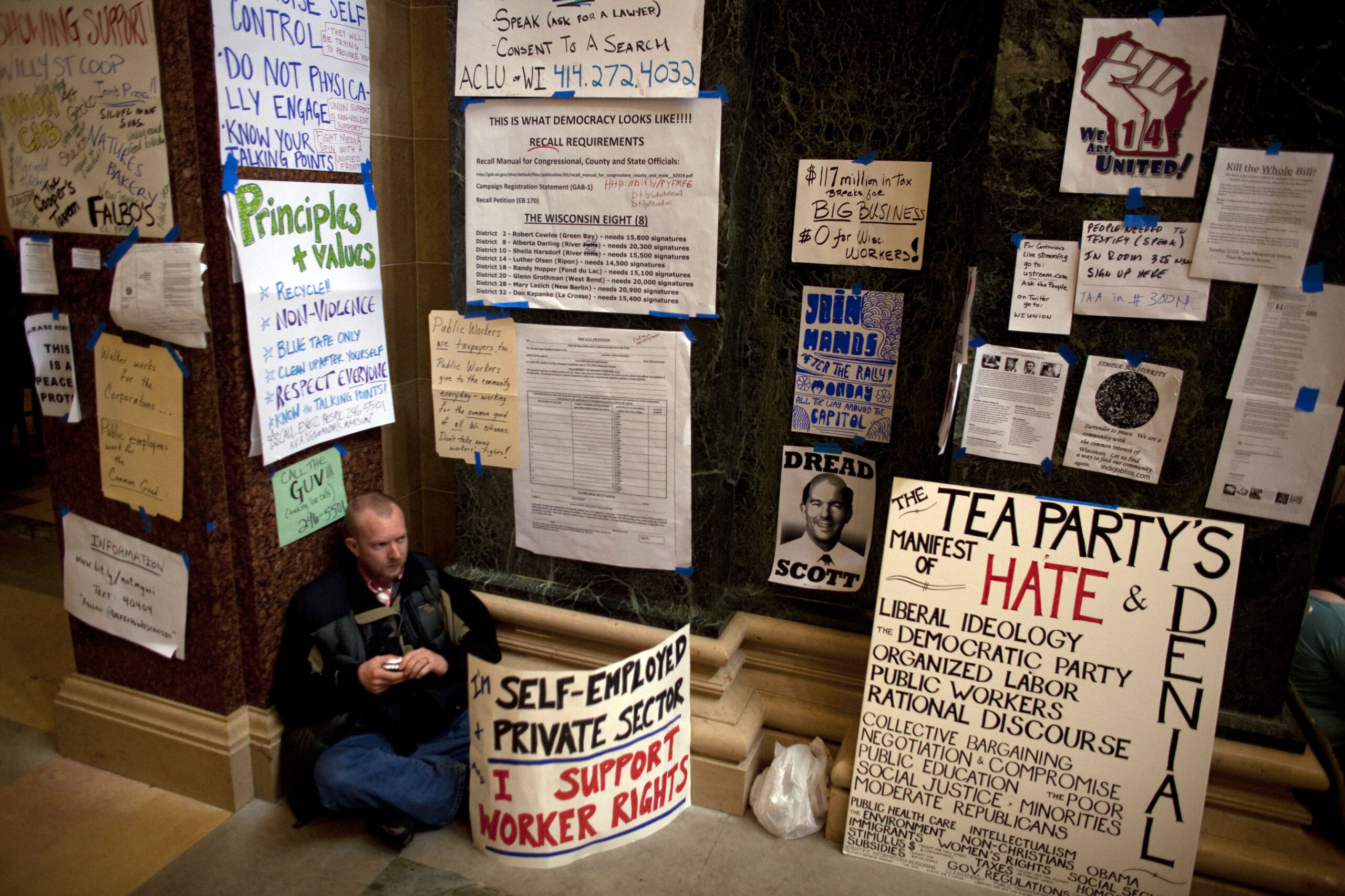 A man sits surrounded by protester signs on day eight of protests against the budget cuts proposed by Wisconsin Governor Scott Walker (Rep.) at the state Capitol in Madison, Wisconsin February 22, 2011. The Wisconsin state Assembly on Tuesday opened debate on a Republican proposal to curb the power of public sector unions that has sparked mass demonstrations and a tense stand-off with Democrats. REUTERS/Darren Hauck (UNITED STATES - Tags: POLITICS CIVIL UNREST) (Reuters)