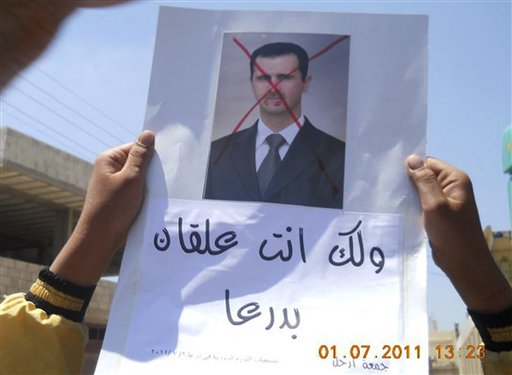In this citizen journalism image made on a mobile phone and provided by Shaam News Network, anti-Syrian President Bashar Assad protester, holds up an Arabic placard read:"You are stuck in Daraa," during a demonstration against the Syrian regime, at Tafas village in Daraa province, southern Damascus, Syria, on Friday July 1, 2011. Hundreds of thousands of protesters flooded cities around Syria on Friday in one of the largest outpourings against the regime of President Bashar Assad since the uprisings began more than three months ago. At least six people were killed in various clashes, activists said. (AP Photo/Shaam News Network) EDITORIAL USE ONLY, NO SALES, THE ASSOCIATED PRESS IS UNABLE TO INDEPENDENTLY VERIFY THE AUTHENTICITY, CONTENT, LOCATION OR DATE OF THIS HANDOUT PHOTO (AP)