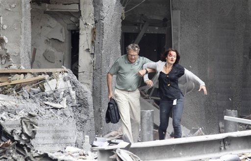 An injured woman is assisted from a damaged building in Oslo, Friday July 22, 2011, after an explosion rocked the capital. Terrorism ravaged long-peaceful Norway on Friday when a bomb ripped open buildings including the prime minister's office and a man dressed as a police officer opened fire at a nearby island youth camp. (AP Photo/Scanpix, Morten Holm) NORWAY OUT (AP)
