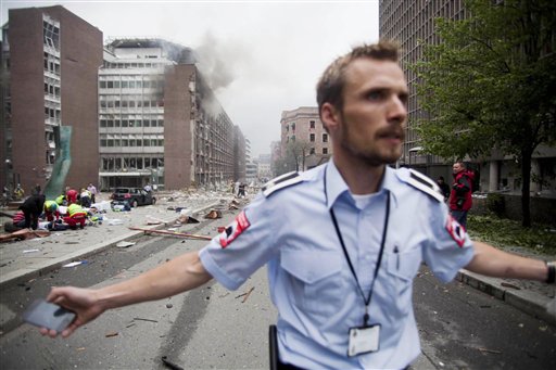 CORRECTS YEAR  An official attempts to clear away spectators from buildings in the centre of Oslo, Friday July 22, 2011, following an explosion that tore open several buildings including the prime minister's office, shattering windows and covering the street with documents.(AP Photo/Fartein Rudjord) NORWAY OUT: (AP)