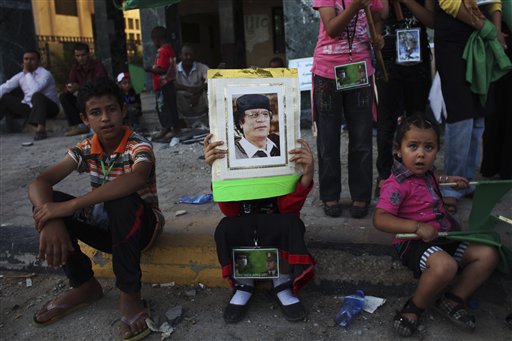 In this photo taken on a government-organized tour, a child rests as she holds up a picture of LIbyan leader Moammar Gadhafi during a rally in the town of Zawiya, roughly 50 km (30 miles) west of Tripoli, Libya, Saturday, July 16, 2011. Ten rebel fighters were killed in an advance on the strategic oil town of Brega in eastern Libya on Saturday, with rebel forces sweeping the outskirts for land mines so they could move in, officials said. The advance came after Libya's main opposition group was recognized by more than 30 nations, including the U.S., as Libya's legitimate government. Friday's decision potentially frees up billions of dollars in cash that the rebels urgently need. (AP Photo/Tara Todras-Whitehill) (AP)