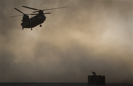 ADDS DATE OF CRASH - FILE - A US Marine tries to take cover, perched on a container, trying to shelter from the dust as a Chinook helicopter arrives to pick up supplies at Forward Operating Base Edi in the Helmand Province of southern Afghanistan, in this June 9, 2011 file photo. Afghan President Hamid Karzai says 31 U.S. special forces and seven Afghan soldiers were killed when a helicopter, similar to the one shown crashed in eastern Wardak province Saturday Aug. 6, 2011.  (AP Photo/Anja Niedringhaus, File) (AP)