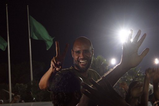 Moammar Gadhafi's son, Seif al-Islam gestures to troops loyal to his father in Tripoli, Libya, Tuesday, Aug. 23, 2011. Seif al-Islam, who was earlier reported arrested by Libya's rebels, turned up early Tuesday morning at the hotel where foreign journalists stay in Tripoli, then took reporters in his convoy on a drive through the city. (AP Photo/Imed Lamloum, Pool) (AP)