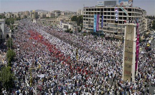 FILE- In this Friday, July 22, 2011, a citizen journalism image made on a mobile phone and provided by Shaam News Network, Syrian anti-regime protesters gather during a rally in al-Assy square in the western city of Hama, Syria. The Arabic on banner reads:"we will never forget our martyrs and prisoners." Activist Ibrahim Qashoush's lyrics moved thousands of protesters in Syria who sang his jaunty verses at rallies, telling President Bashar Assad, "Time to leave." So when his body was dumped in the river flowing through his hometown, his killers added an obvious message: His throat was carved out.  Qashoush's slaying underlines how brutal Syria's turmoil has become as authorities try to crush a persistent uprising. His fellow activists are convinced he was killed by security forces and fear it could mark a new campaign to liquidate protest leaders.(AP Photo/Shaam News Network, File) EDITORIAL USE ONLY, NO SALES, THE ASSOCIATED PRESS IS UNABLE TO INDEPENDENTLY VERIFY THE AUTHENTICITY, CONTENT, LOCATION OR DATE OF THIS HANDOUT PHOTO (AP)