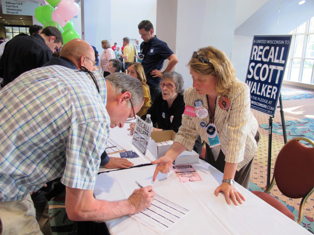 Ron Heitz, 59, of Waukesha, Wis., attends the state Democratic Partyâs annual convention in Milwaukee on Friday, June 3, 2011, where he signs a pledge to support an eventual recall of Wisconsin Gov. Scott Walker. Lynn Freeman, 43, of Madison, explains to him how the process will work. Democrats want to recall six Republican state senators this summer, and they hope to also recall Walker next year because of his efforts to strip most public employees of collective-bargaining rights. About 1,000 Democrats gathered in Milwaukee on Friday for a convention billed as a prelude to recalling Republican Gov. Scott Walker and six GOP state senators.  (AP Photo/Dinesh Ramde) (Dinesh Ramde)