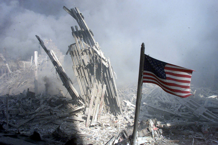 Am American flag flies near the base of the destroyed World Trade Center in New York, September 11, 2001. Planes crashed into each of the two towers, causing them to collapse. (Â© Peter Morgan / Reuters)