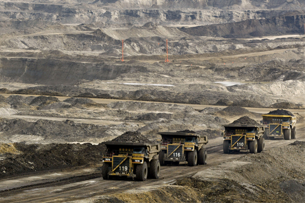 Mining trucks carry loads of oil laden sand in Alberta, Canada.