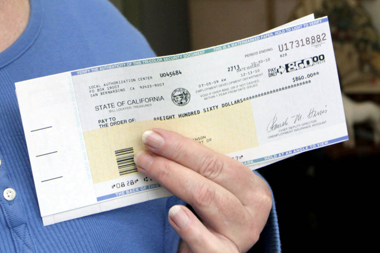In this Dec. 17, 2010 photo,  Theresa Christenson holds an unemployment check in her home in Burbank, Calif.  Before she was laid off from a quality assurance job at Yahoo in July 2009, Christenson earned around $100,000 a year. The 58-year-old has managed to hang on to the 4-bedroom house that she co-owns with her sister, where they've lived for 22 years. "It really gets me when they say 'you lazy people,'" says Christenson, who lives on $1,720 a month in unemployment insurance benefits and what's left of her dwindling 401K. "They have no idea how depressing that is when you have been beating your head against the wall, trying to find work.  (AP Photo/Nick Ut) (Nick Ut)