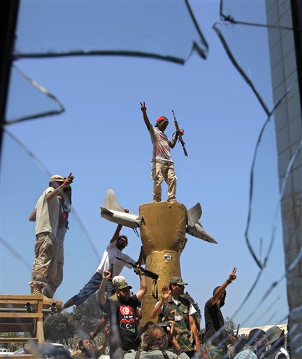 Rebel fighters celebrate as they stand on top of the monument inside the main Moammar Gadhafi compound in Bab Al-Aziziya in Tripoli, LIbya, Wednesday, Aug. 24, 2011. The rebels say they have now taken control of nearly all of Tripoli, but sporadic gunfire could still be heard Wednesday, and Gadhafi loyalists fired shells and assault rifles at fighters who had captured the Libyan leader's personal compound one day earlier. (AP Photo/Sergey Ponomarev) (AP)