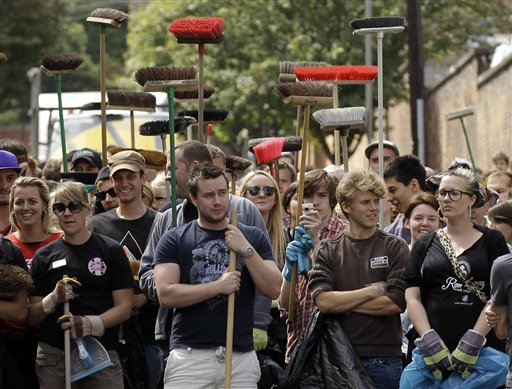 London residents wait to be allowed through a police cordon to help council workers with the clear up after rioting in Battersea, London, Tuesday, Aug. 9, 2011