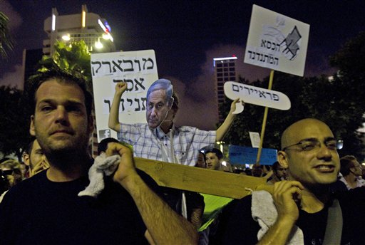 Israelis march with a stretcher with a person wearing a mask of Israel's Prime Minister Benjamin Netanyahu during a protest in central Tel Aviv, Saturday, July 30, 2011