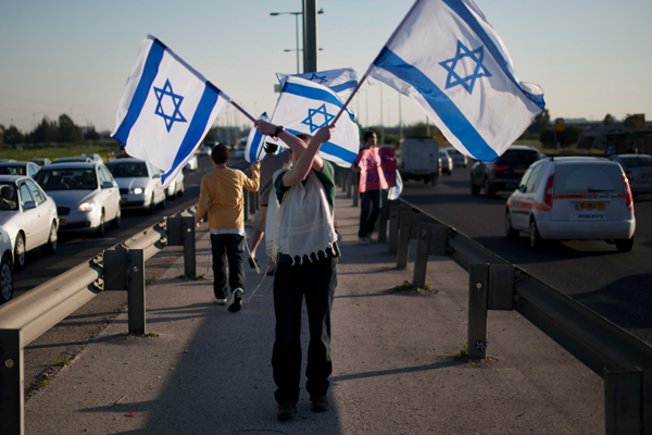 A Jewish settler holds Israeli flags as he protests in support of the Jewish settlers in the West Bank.