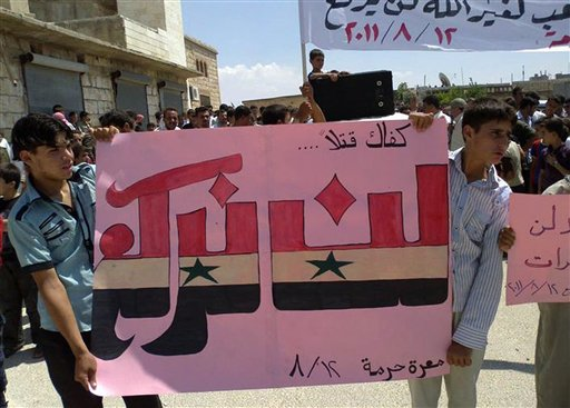 Anti-Syrian President Bashar Assad protesters hold up an Arabic banner reading: "Enough killing, will not bow" on Friday, August 12, 2011