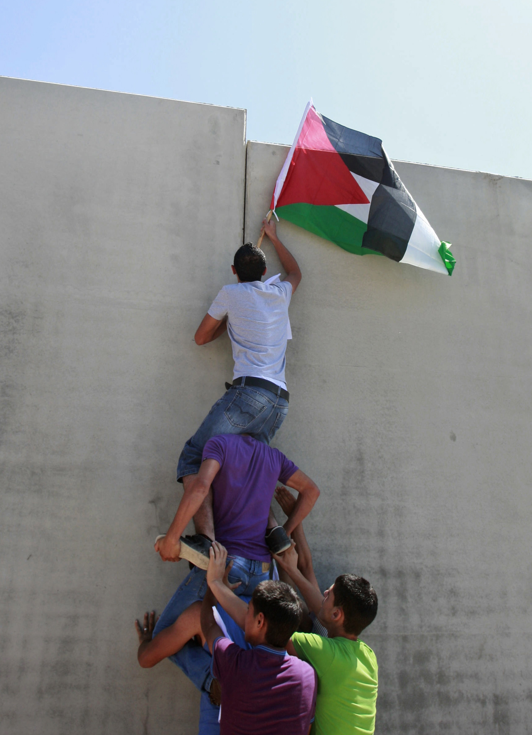 A Palestinian holding a national flag climbs the separation barrier during a protest against its construction in the West Bank village of Walajeh, outside Jerusalem. Friday, Sept. 16, 2011. (AP Photo/Nasser Shiyoukhi) (Associated Press)