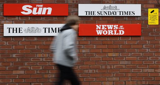 FILE - This is a Thursday, Jan. 27, 2011 file photo of a  pedestrian he passes signs at the entrance to News International in Wapping, London.   Rupert Murdoch's News International said Monday Sept. 5, 2011 it will sell its complex in the east London area of Wapping.The company says it will relocate to another area in east London.The company says in a statement that "current market conditions" led to a decision "not to proceed with remodeling the Wapping site." (AP Photo/Kirsty Wigglesworth, File) (AP)