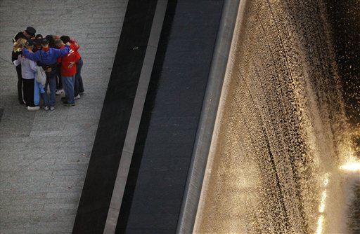 People pause by the waterfall pool at the National September 11 Memorial before a planned ceremony marking the 10th anniversary of the attacks at the World Trade Center site, Sunday, Sept. 11, 2011, in New York. (AP Photo/Matt Rourke) (AP)