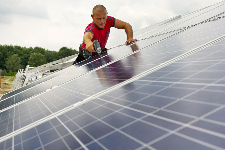 A worker fixes solar modules at a solar park in Spremberg, Germany