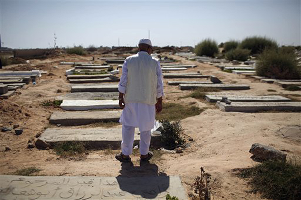 Mashud Marjub Orabi, retired oil company worker, stands next to the grave of his son and other rebel fighters, who he says were killed in Tripoli fighting against Moammar Gadhafi's troops, at a cemetery on the first day of Eid al-Fitr in Tripoli, Libya, Wednesday, Aug. 31, 2011. Muslims are celebrating the festival of Eid al-Fitr which marks the end of the holy fasting month of Ramadan. (AP Photo/Alexandre Meneghini) (Alexandre Meneghini)
