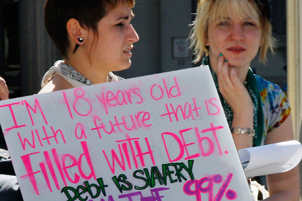 Two young women sit next to a sign as they listen to a speakers during a protest gathering across from the Statehouse in Trenton, N.J., Thursday, Oct. 6, 2011, as the "Occupy Wall Street" movement in New York has spread across the Hudson River.