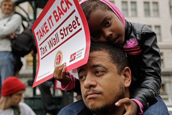 Kamayah Riley, 5, rests atop her father Manuel Riley's shoulders as he they participate in an Occupy Oakland rally. (AP/Ben Margot)