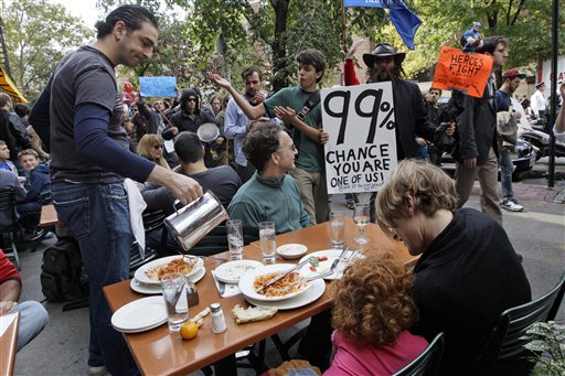 Demonstrators affiliated with the Occupy Wall Street march past a family dining at an outdoor restaurant, Saturday, Oct. 15, 2011 in New York (AP Photo/Mary Altaffer)