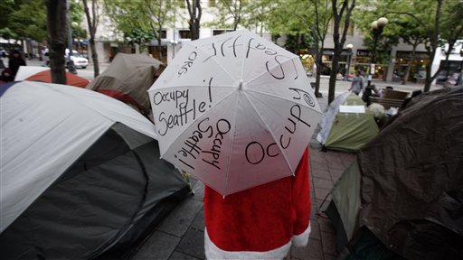 Miles Partman carries an umbrella with "Occupy Seattle" written on it as he walks though an encampment in downtown Seattle's Westlake Park,  Wednesday, Oct. 5, 2011. (AP/Ted S. Warren)