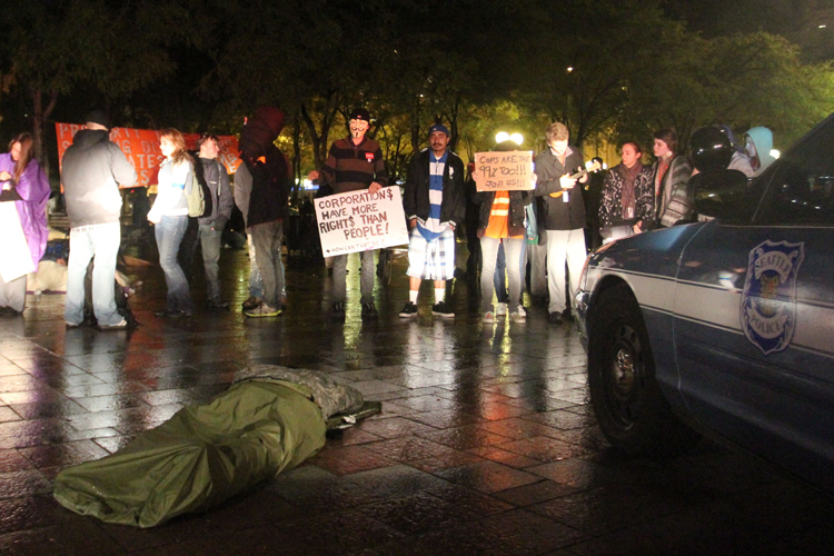 Several Occupy Seattle protesters stand in front of Seattle Police patrol cars in Westlake Park in downtown Seattle early Tuesday Oct. 11, 2011. (AP/Manuel Valdes)