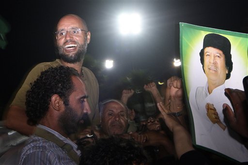 File - Moammar Gadhafi's son, Seif al-Islam, top left, gestures to troops loyal to his father in Tripoli, Libya, Tuesday, Aug. 23, 2011. (AP/Imed Lamloum)
