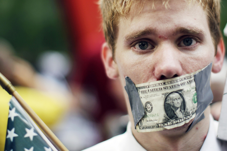 A demonstrator from the Occupy Wall Street campaign stands with a dollar taped over his mouth as he stands in Zucotti Park near the financial district of New York September 30, 2011. (Lucas Jackson / Reuters)