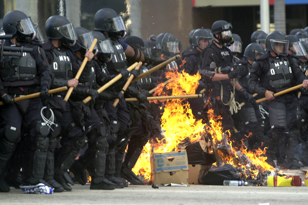 Miami riot police march through burning trash during a free trade protest in November 2003. (AP)