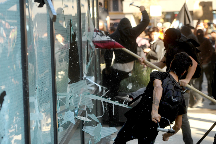 A small group of Occupy Oakland protesters smash windows at a Wells Fargo bank branch on Wednesday, Nov. 2, 2011, in Oakland, Calif. (Noah Berger/AP)