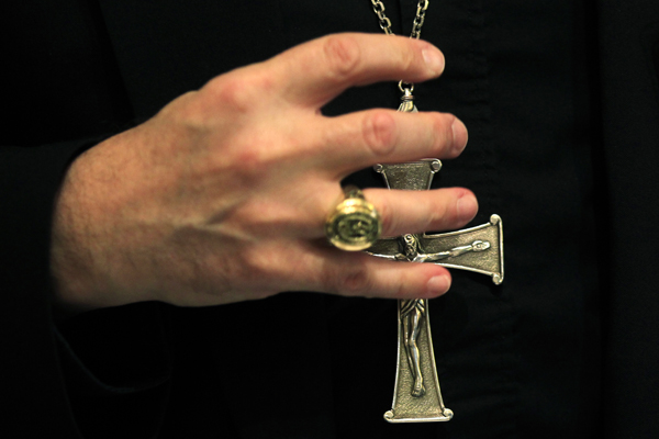 A bishop grasps his pectoral cross during the United States Conference of Catholic Bishops in Baltimore (Kevin Lamarque / Reuters)