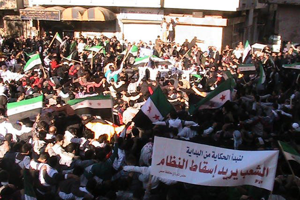 Demonstrators protesting against Syria's President Bashar al-Assad wave the old Syria flag as they march through the streets on the first day of the Muslim festival of Eid-al-Adha in Alsnmin near Daraa November 6, 2011. The banner reads, "People want the regime to step down". (Reuters)