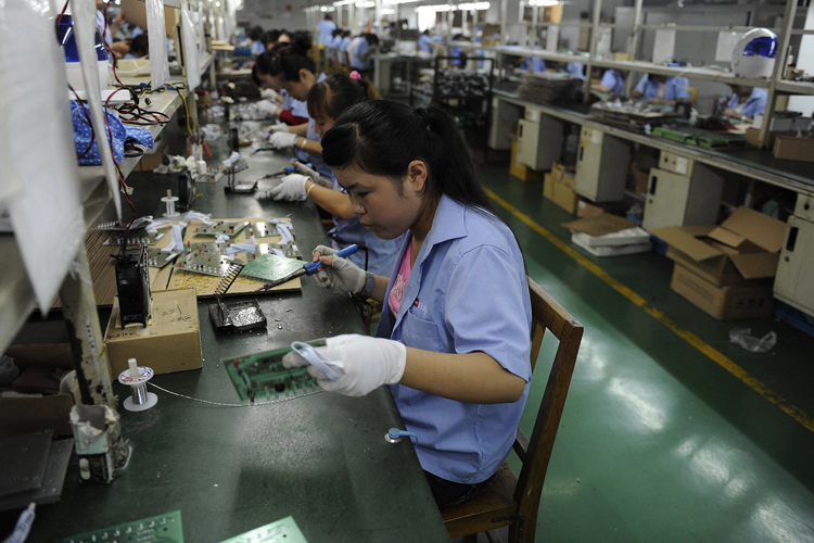 An employee works on circuit boards at an electronic component factory in Hefei, Anhui province, China. (Jianan Yu / Reuters)