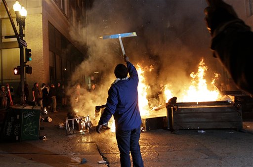 An Occupy Oakland protester holds up a sign in front of a bonfire in Oakland, Calif., Thursday, Nov. 3, 2011. (AP/Jeff Chiu)
