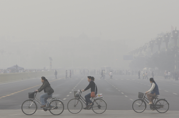 Chinese women cycle through smog and pollution over Beijing's Tiananmen Square (AP)
