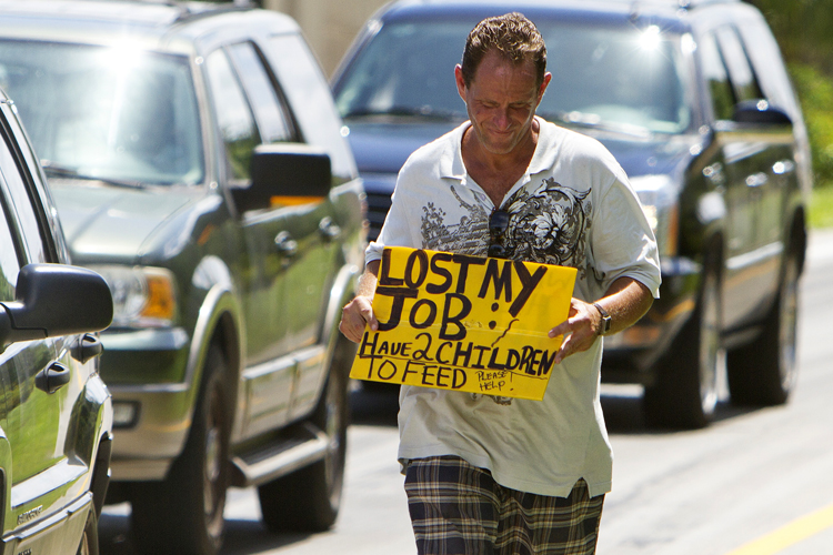 A man who did not wish to be identified, who lost his job two months ago after being hurt on the job, works to collect money for his family on a Miami street corner (AP/J Pat Carter)