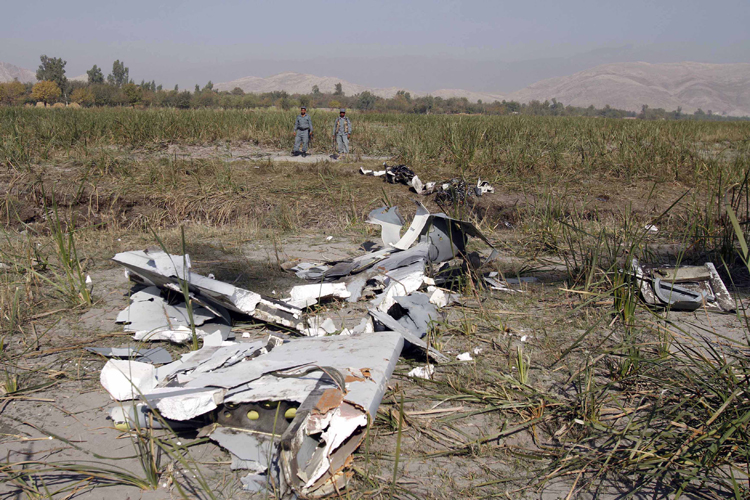 Afghan policemen stand guard near the remains of a US Predator, an unmanned drone, after it crashed on the outskirts of Jalalabad, east of Kabul, Afghanistan, Wednesday, Nov 2, 2010. (AP/Rahmat Gul)