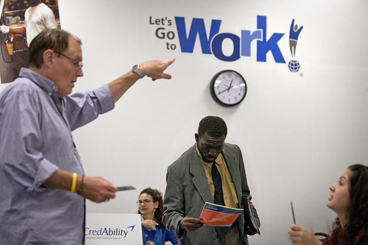 In this Oct. 4, 2011 photo, Snotti St. Cyr, center, looks over a brochure while attending a job fair at a Goodwiill store in Atlanta. The number of people who applied for unemployment benefits rose slightly last week, a sign that the job market remains weak. (AP Photo/David Goldman) (David Goldman)