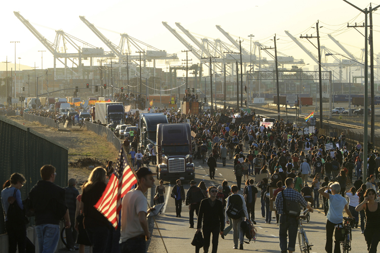 A demonstrator carries a U.S. flag as thousands of people converge on the Port of Oakland, California (Robert Galbraith / Reuters)